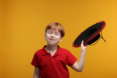 Photo of Cute boy with Mexican sombrero hat on yellow background