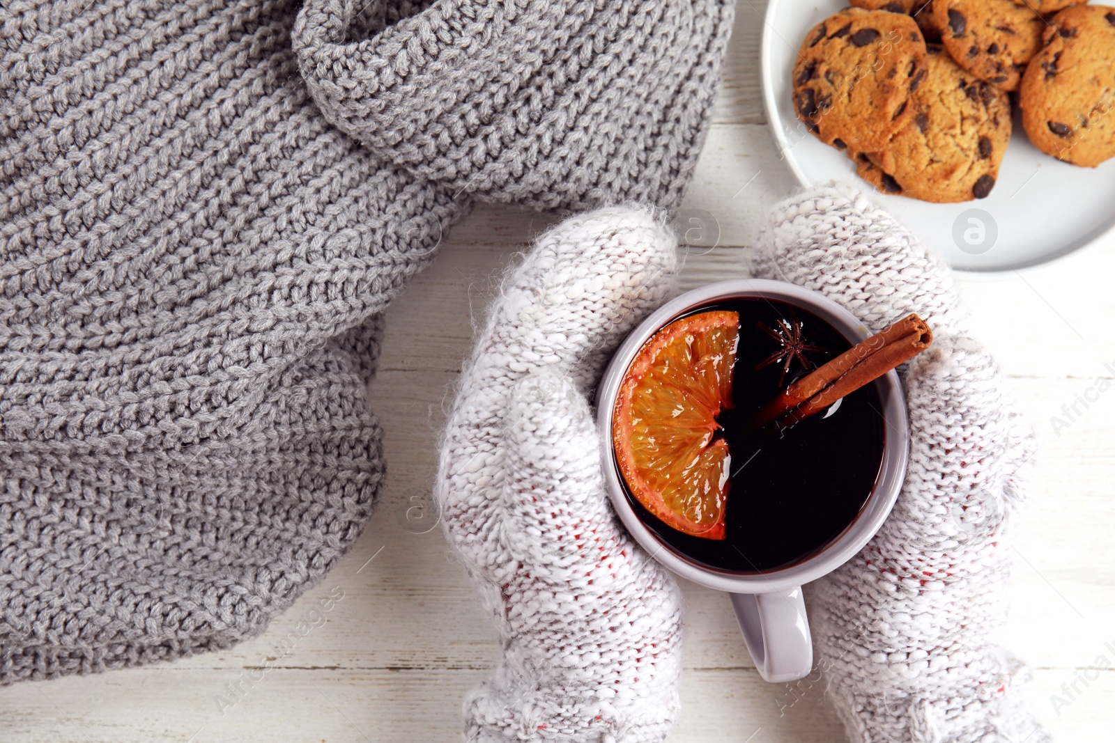 Photo of Woman with cup of hot mulled wine at white wooden table, top view. Winter drink