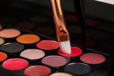 Photo of Colorful eyeshadow palette with brush, closeup view