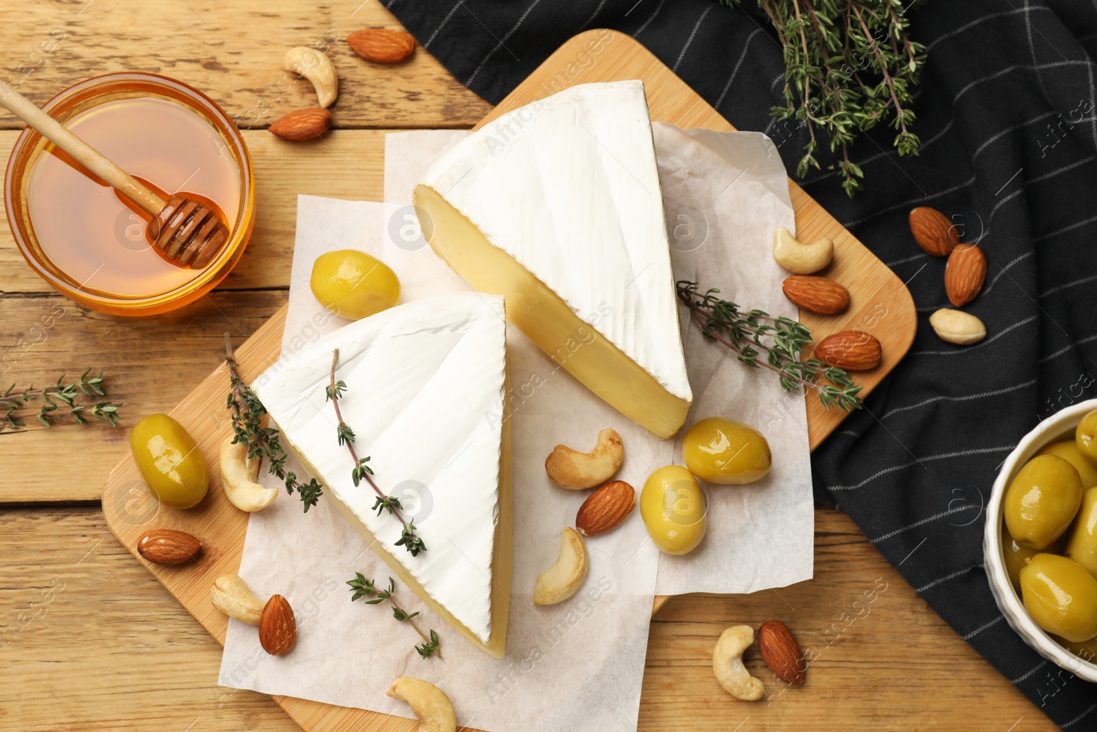 Photo of Tasty Camembert cheese with thyme, honey and nuts on wooden table, flat lay