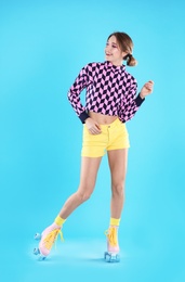 Young woman with retro roller skates on color background