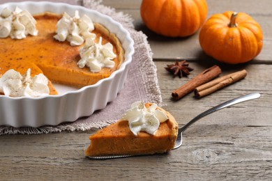 Delicious pie with pumpkins, whipped cream and spices on wooden table