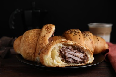 Photo of Tasty croissants with chocolate and sesame seeds on wooden table, closeup