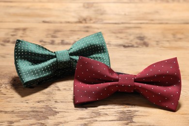 Different stylish bow ties on wooden table