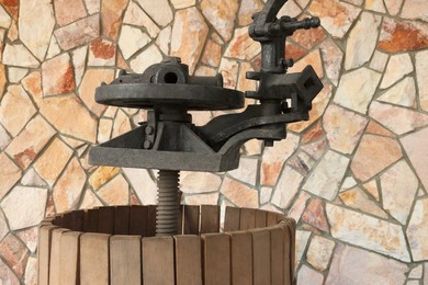 Photo of Metal winepress in wooden barrel near stone wall