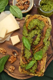 Photo of Freshly baked pesto bread with basil and cheese on table, flat lay