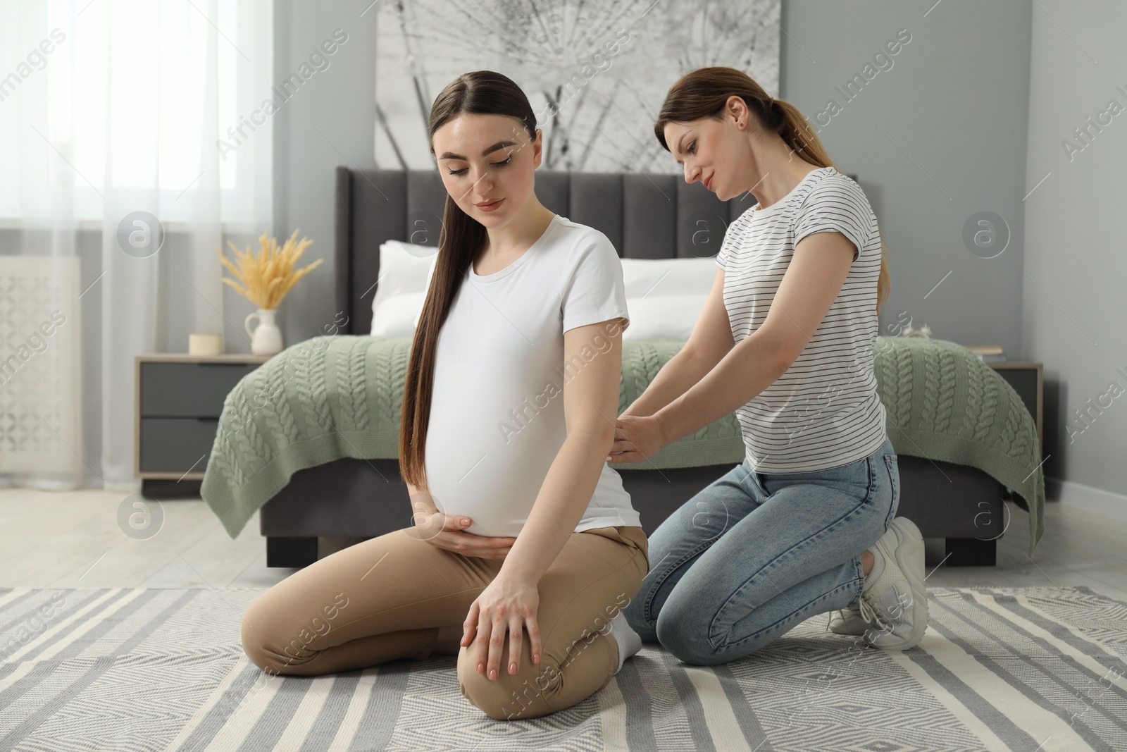 Photo of Doula massaging pregnant woman in bedroom. Preparation for child birth