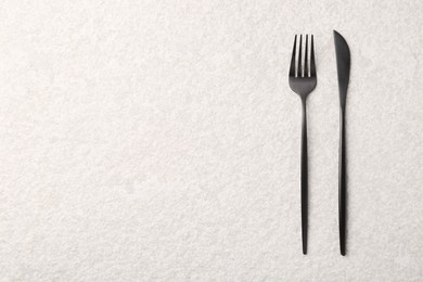 Photo of Stylish cutlery on beige textured table, top view. Space for text