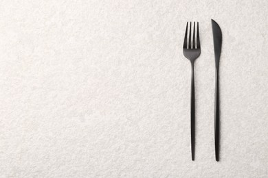 Stylish cutlery on beige textured table, top view. Space for text