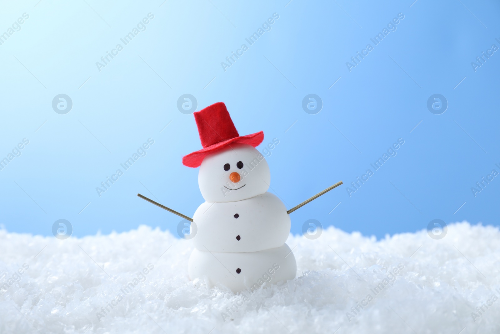 Photo of Funny snowman on snow against light blue background