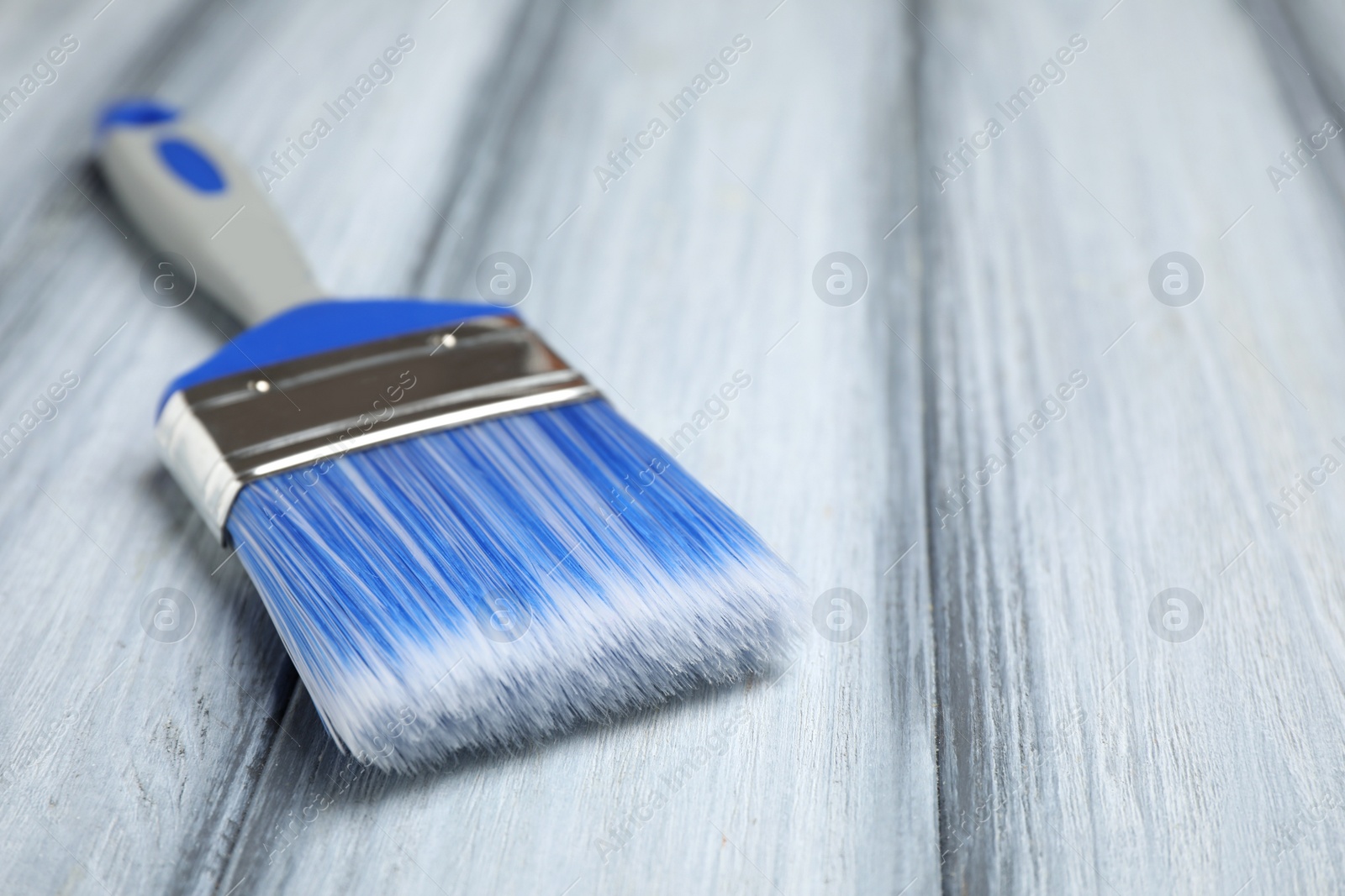 Photo of New paint brush on grey wooden table, closeup. Space for text