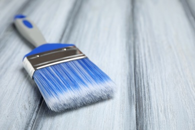 New paint brush on grey wooden table, closeup. Space for text