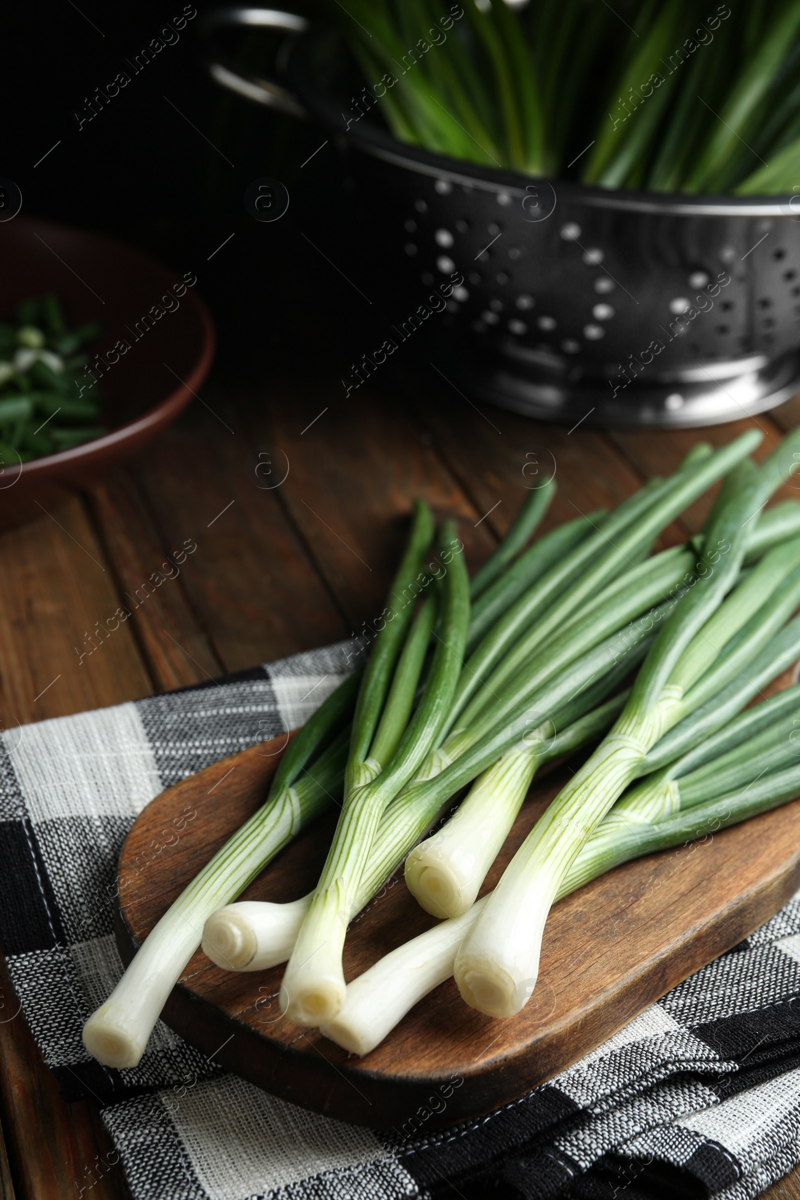 Photo of Fresh green spring onions on wooden board