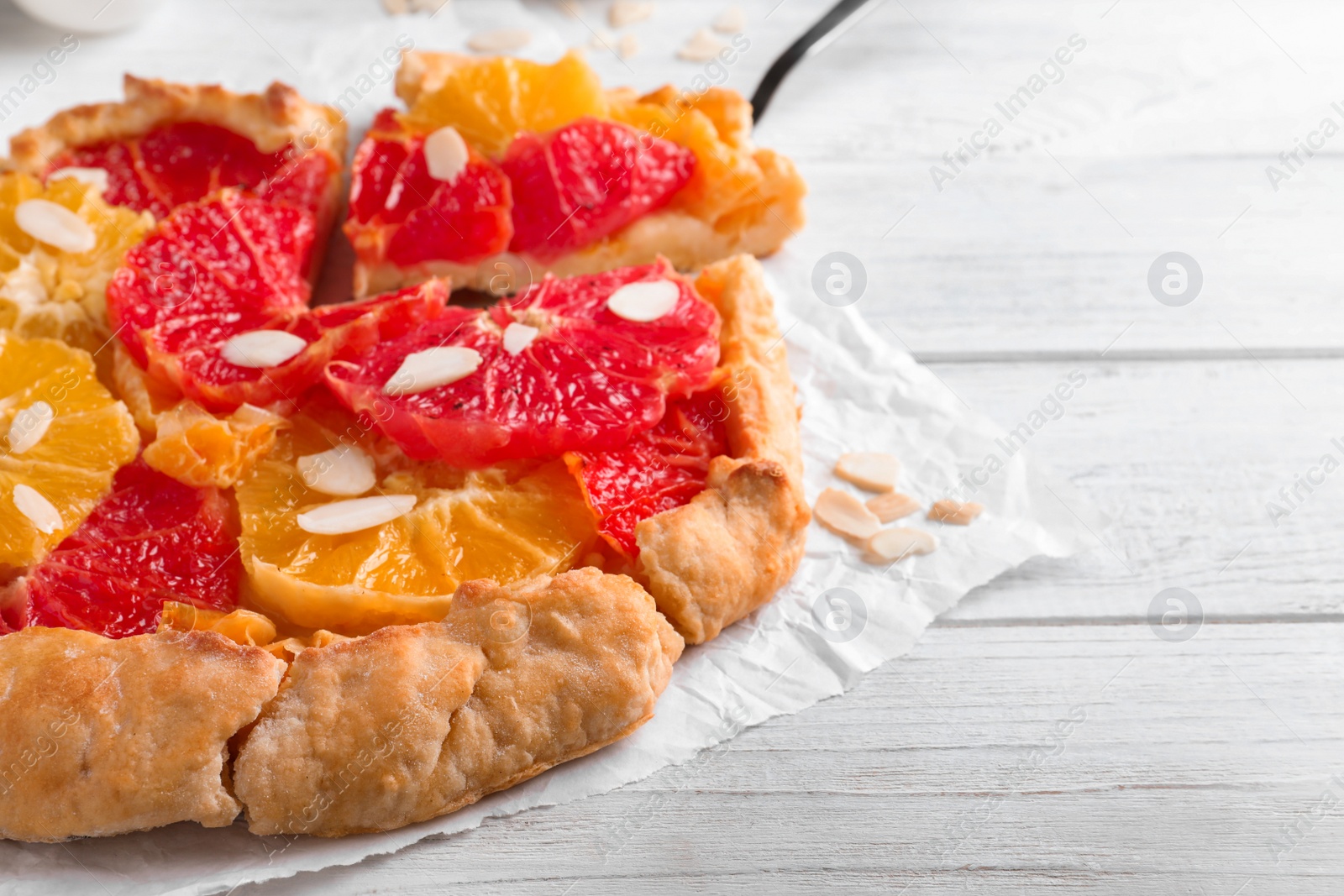Photo of Tasty galette with citrus fruits on white table, closeup