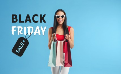 Image of Black Friday Sale. Beautiful young woman with shopping bags on light blue background 