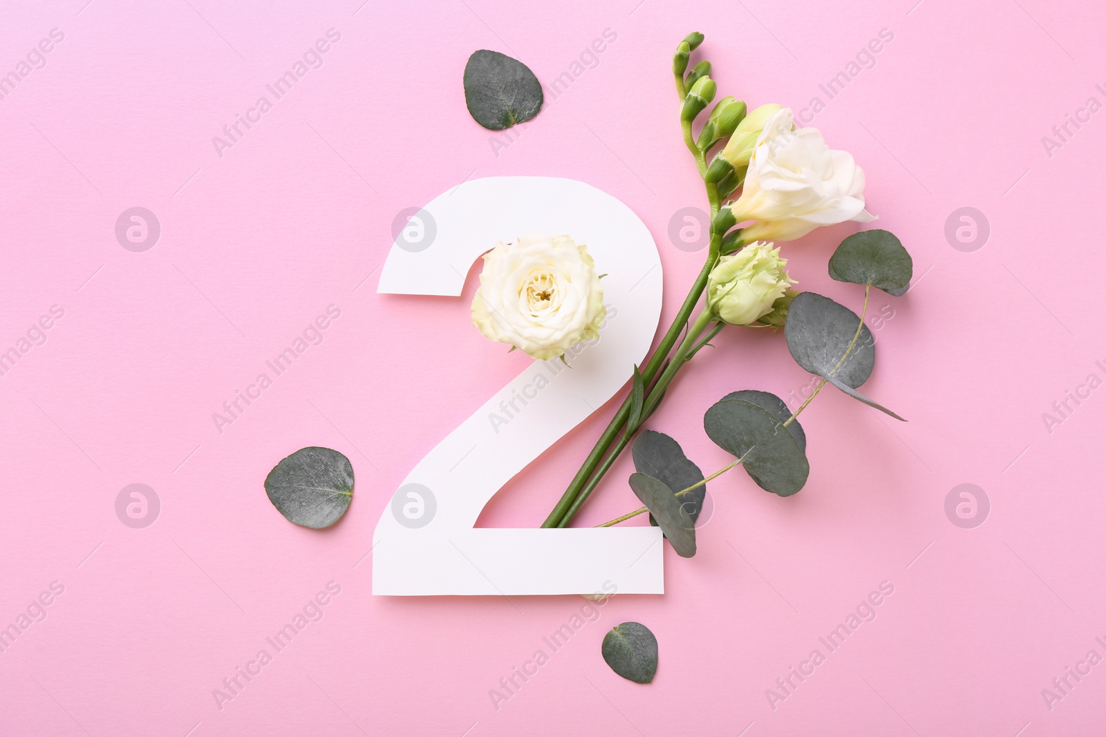 Photo of Paper number 2, eucalyptus leaves and beautiful flowers on pink background, flat lay