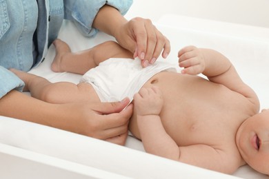 Photo of Mother changing her baby's diaper on table at home, closeup