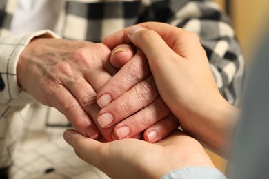 Photo of Young and elderly women holding hands, closeup