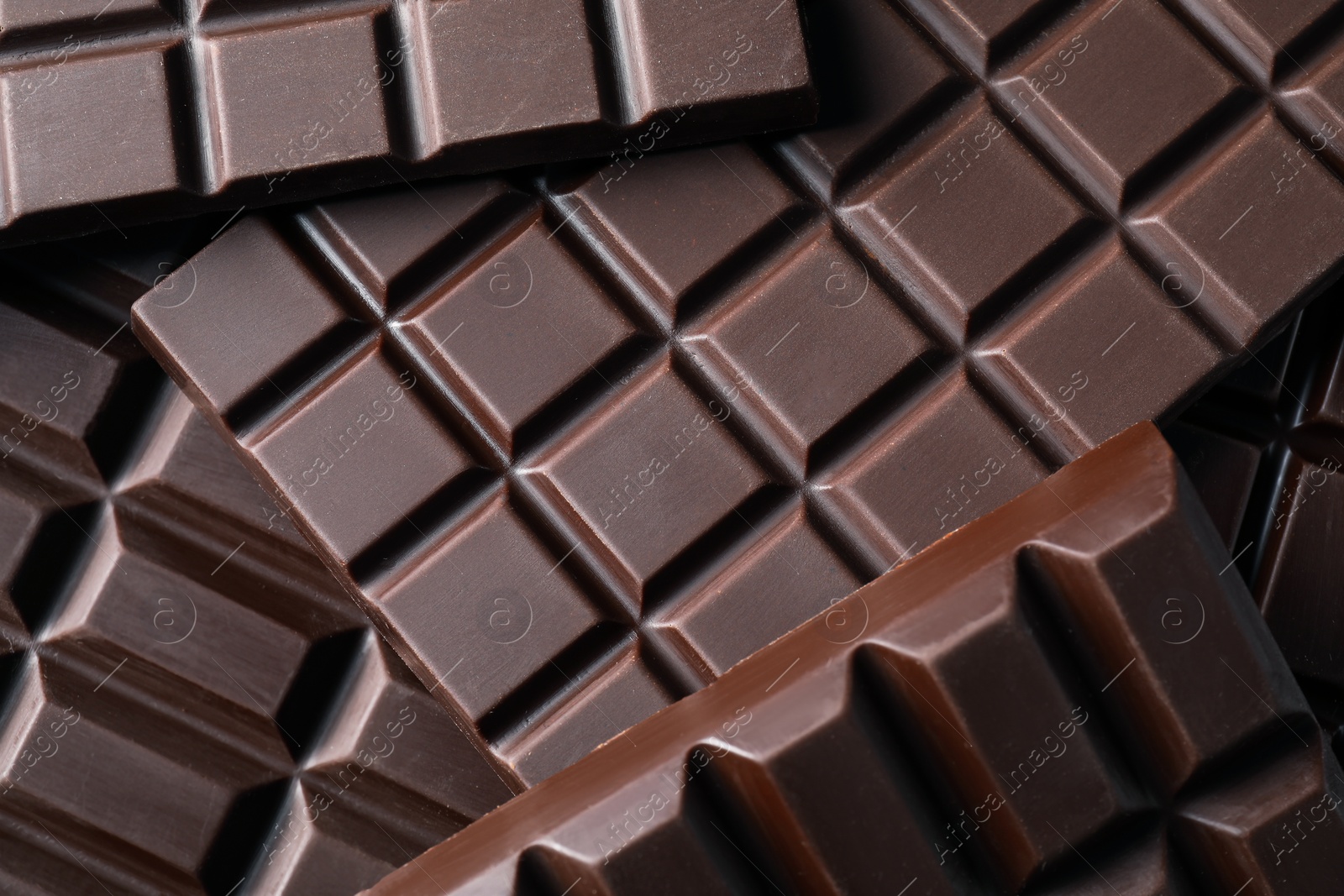 Photo of Many delicious dark chocolate bars as background, top view