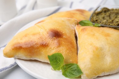 Photo of Delicious samosas with basil and pesto sauce on white table, closeup