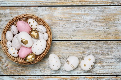Decorative nest and many painted Easter eggs on rustic wooden table, flat lay. Space for text