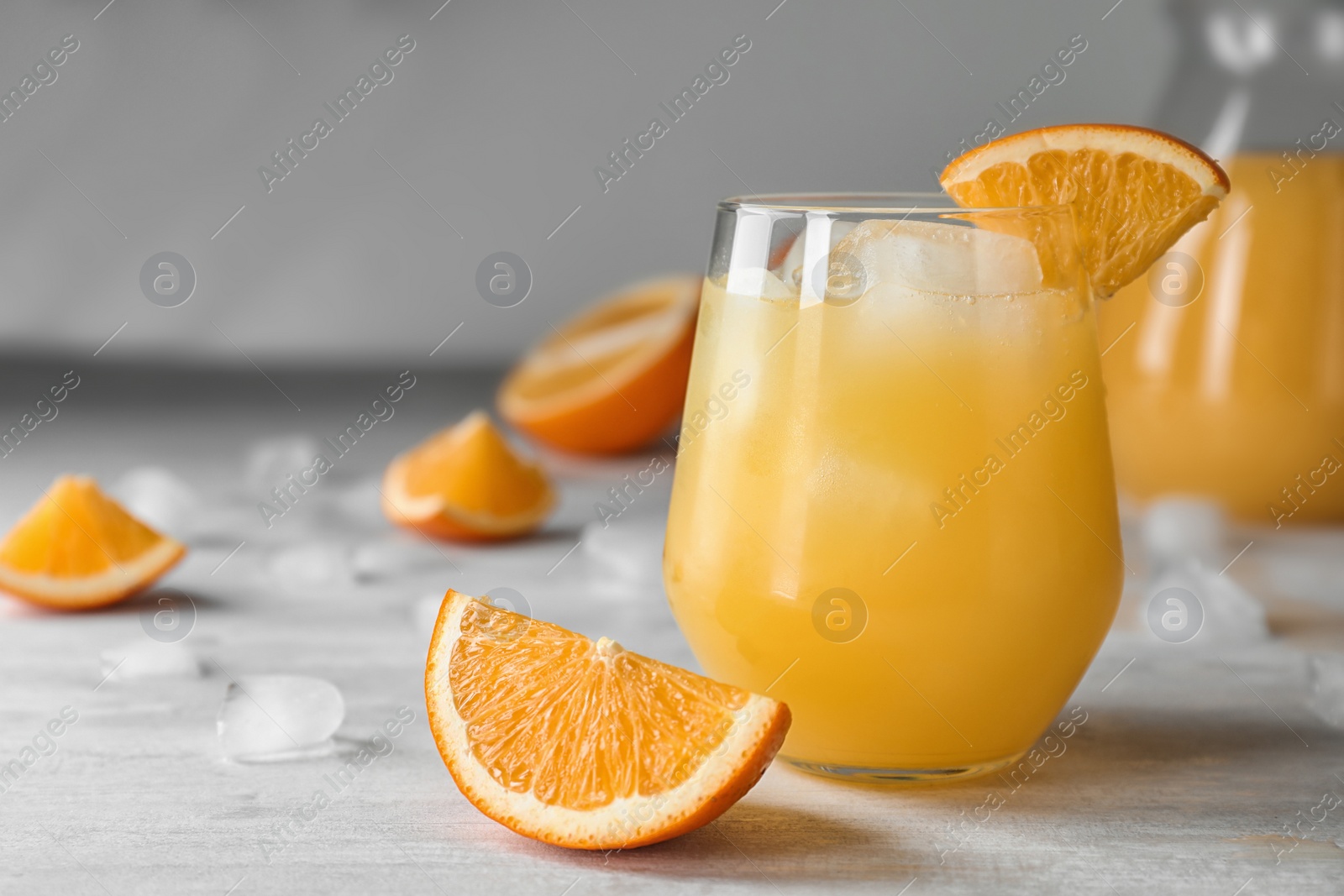 Photo of Glass of orange juice with ice cubes and cut fruit on table. Space for text