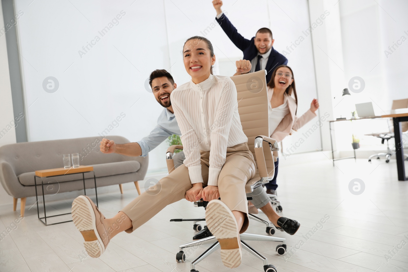 Photo of Happy office employees riding chairs at workplace