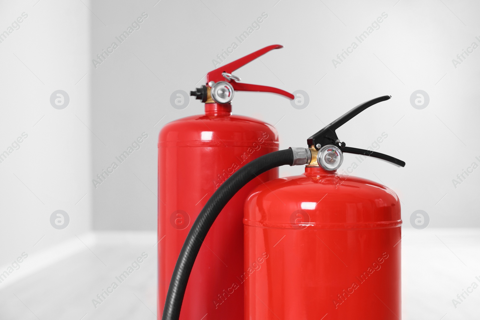 Photo of Two red fire extinguishers indoors, closeup view