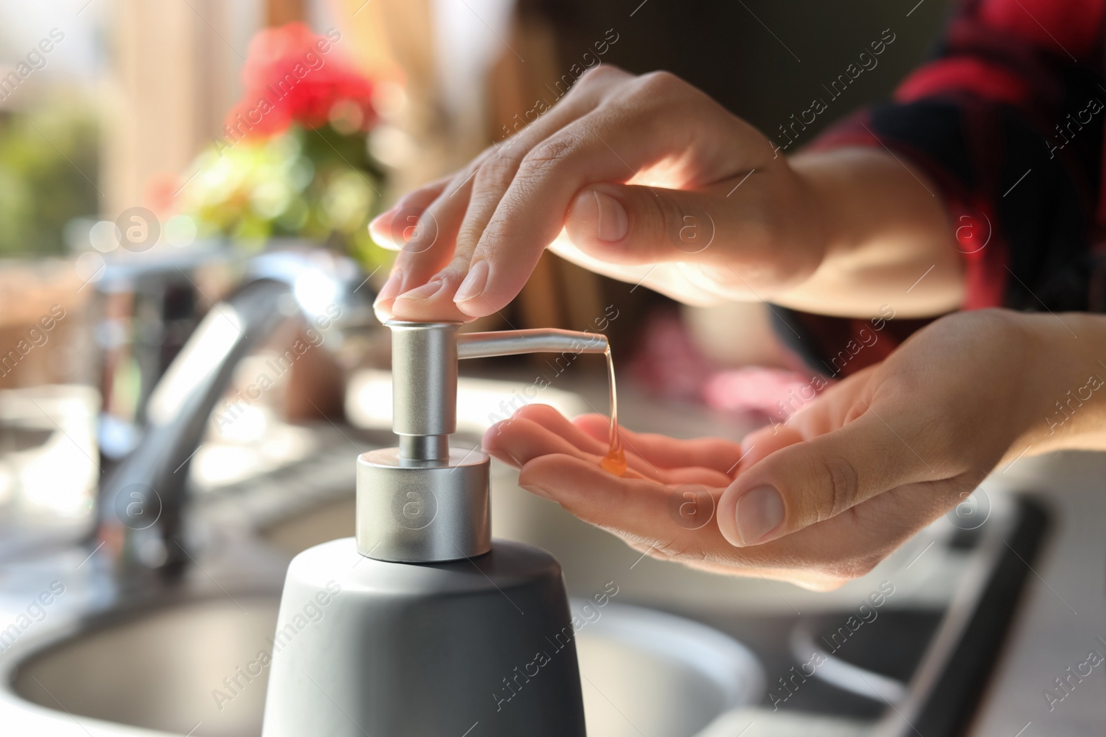 Photo of Woman using liquid soap dispenser in kitchen, closeup