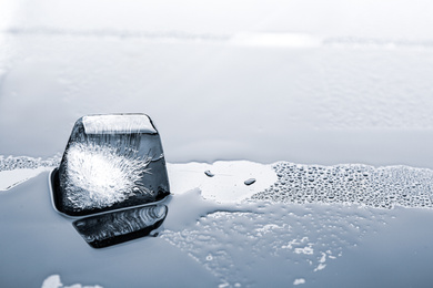 Ice cube on wet grey surface, closeup. Space for text