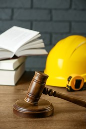 Construction and land law concepts. Gavel, hard hat, measuring tape and books on wooden table
