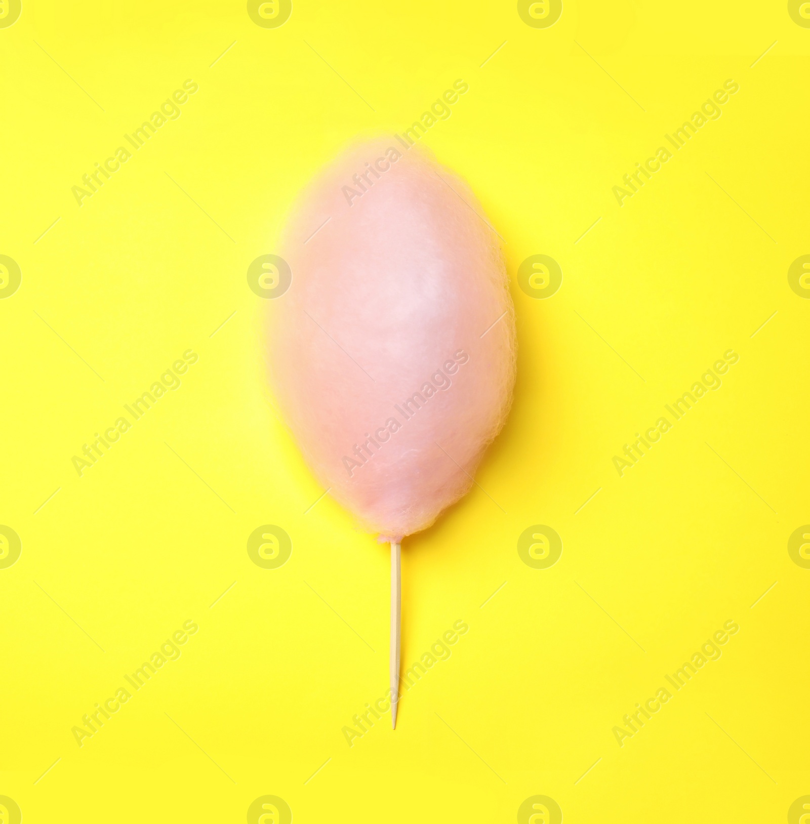 Photo of Sweet pink cotton candy on yellow background, top view