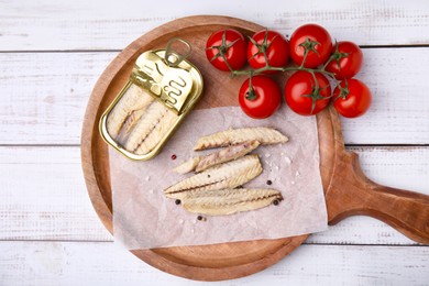 Photo of Delicious canned mackerel fillets and fresh tomatoes on white wooden table, top view
