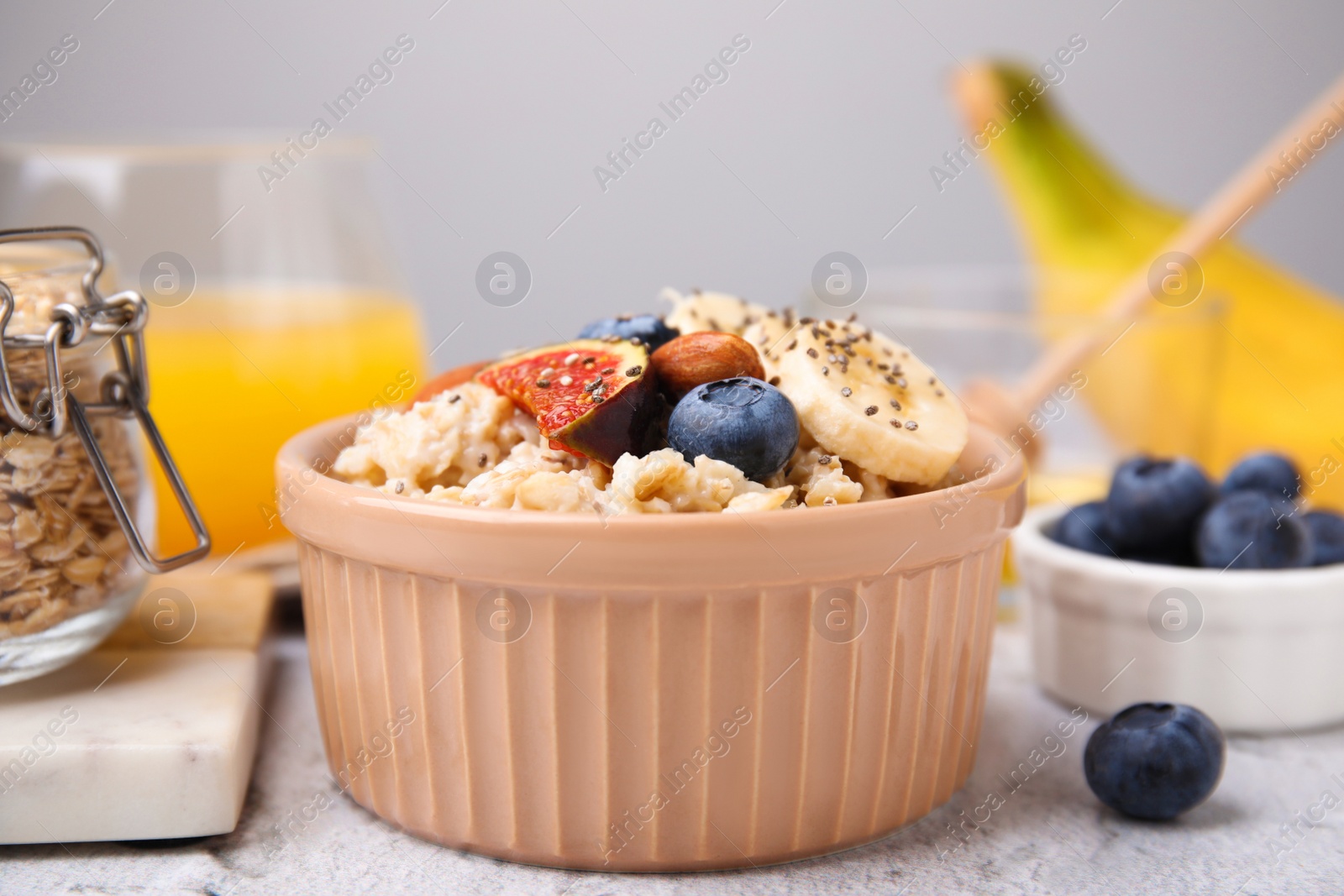 Photo of Bowl of oatmeal with blueberries, almonds, banana and fig pieces on white table, closeup