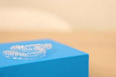 Photo of Transparent dental aligners on beige background, closeup. Space for text