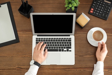 Photo of Man using laptop at table, top view. Space for design