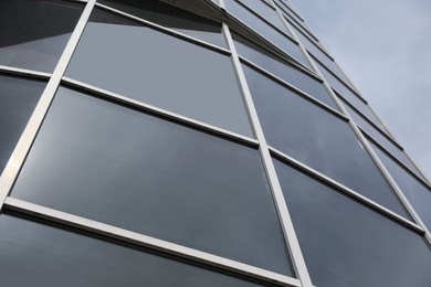 Photo of Modern building with tinted windows, low angle view. Urban architecture