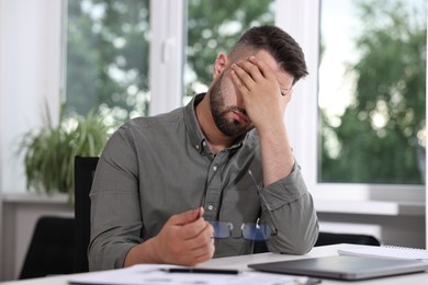 Overwhelmed man sitting at table in office