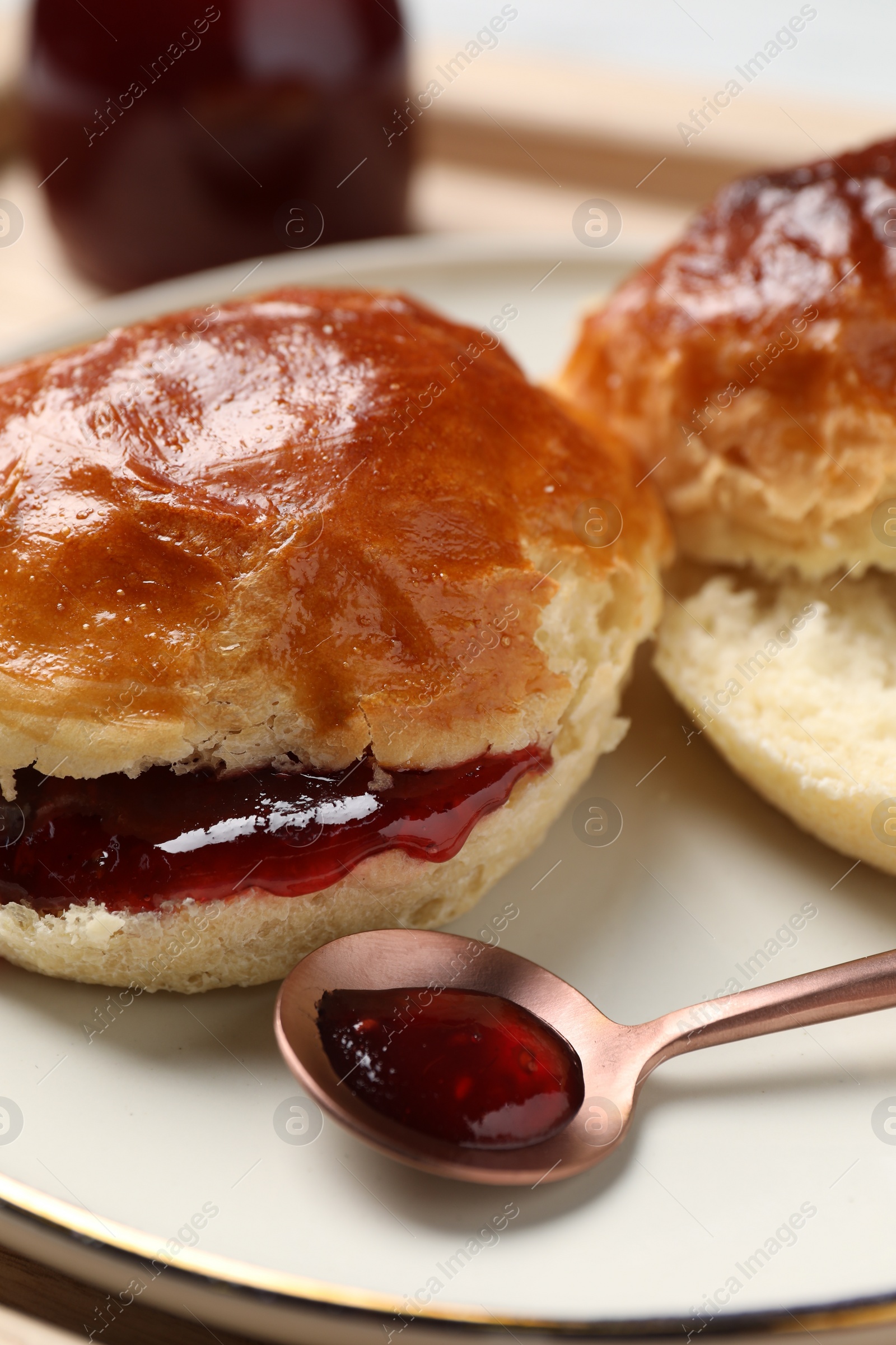 Photo of Freshly baked soda water scones with cranberry jam on wooden table, closeup