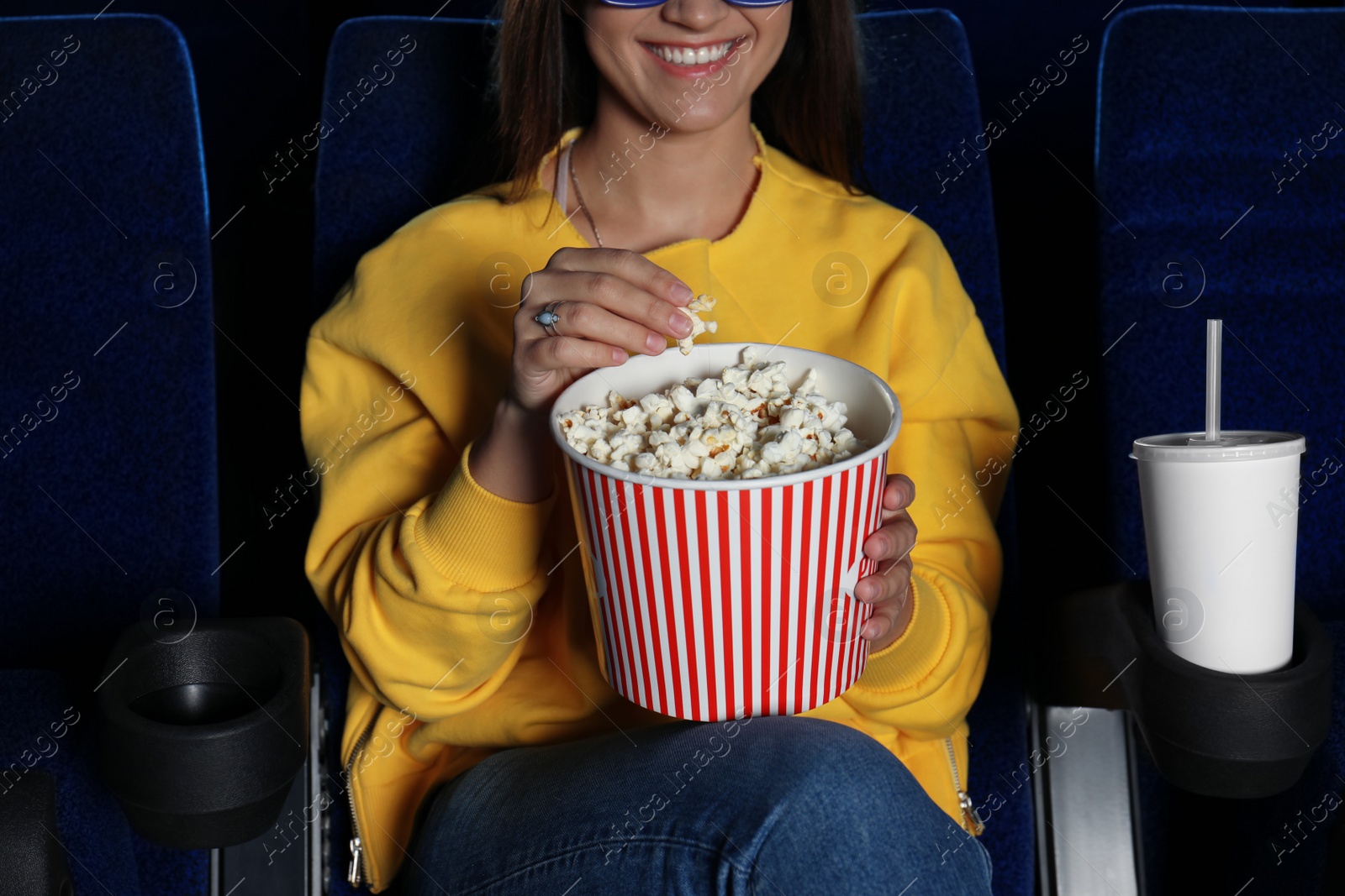 Photo of Young woman with popcorn watching movie in cinema, closeup