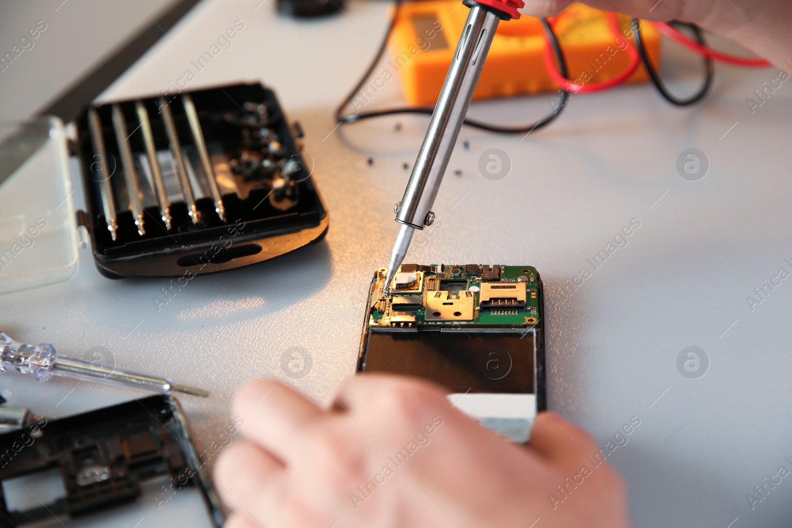 Photo of Technician repairing mobile phone at table, closeup