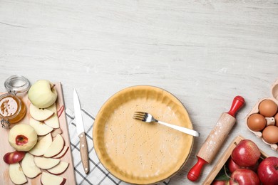 Photo of Flat lay composition with raw dough, fork and ingredients on white wooden table, space for text. Baking apple pie