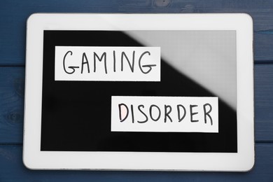 Tablet with phrase Gaming Disorder on blue wooden table, top view. Addictive behavior