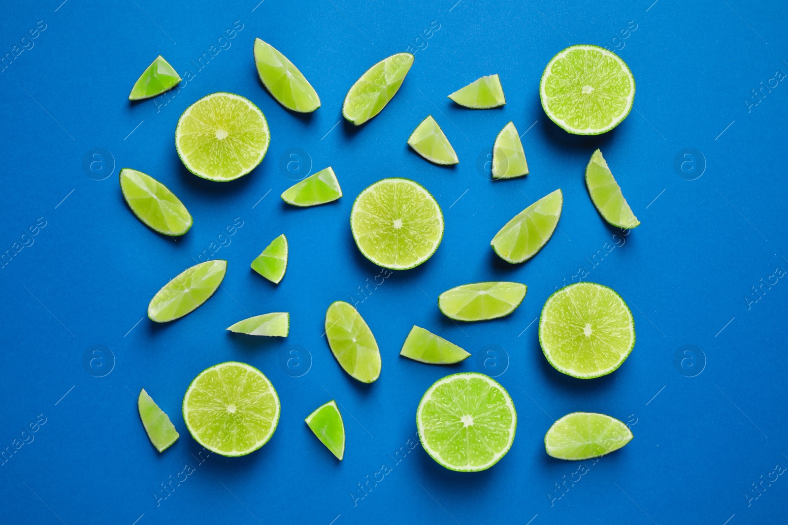 Photo of Juicy fresh lime slices on blue background, flat lay