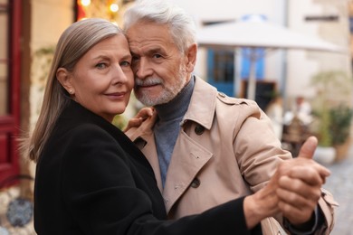 Photo of Affectionate senior couple dancing together on city street