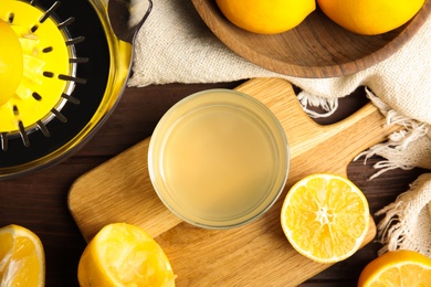 Photo of Freshly squeezed lemon juice on wooden table, flat lay