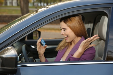 Photo of Happy woman holding driving license in car