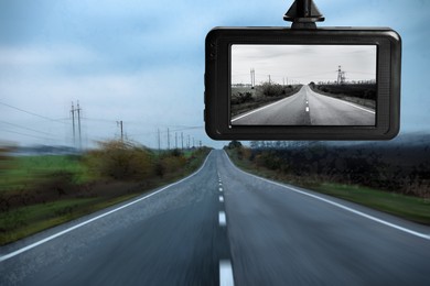 Image of Modern dashboard camera mounted in car, view of road during driving