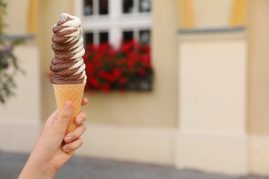 Woman holding delicious ice cream outdoors, closeup. Space for text