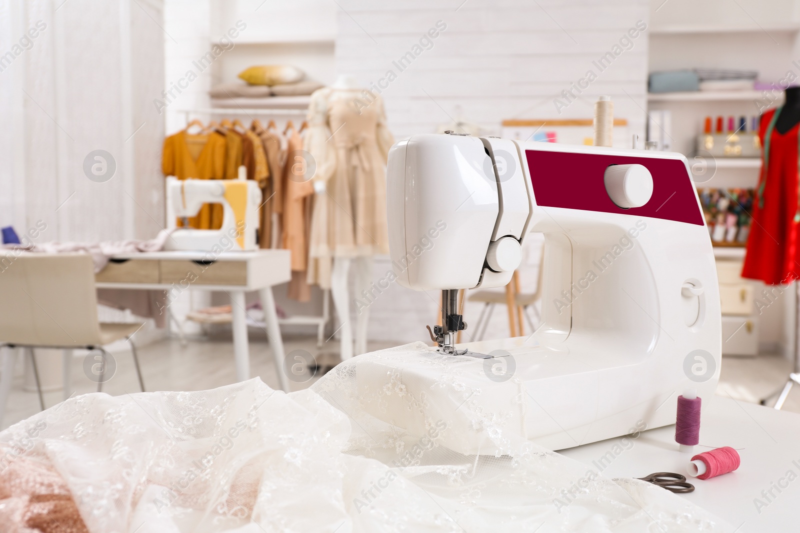 Photo of Modern sewing machine with fabric on table in dressmaking workshop